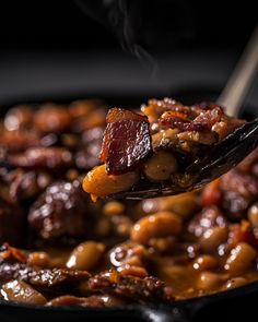 a spoon full of beans and meat in a skillet