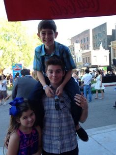 two boys and a girl standing under a coca - cola sign