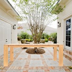 a table sitting in the middle of a patio next to a tree and two doors