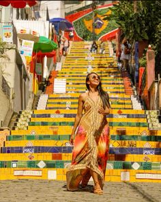 a woman is standing in front of some stairs with colorful tiles on it and smiling