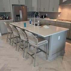 a large kitchen island with four chairs and an oven in the backround area