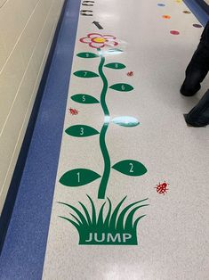 a person walking down a long hallway next to a plant on the floor with numbers painted on it