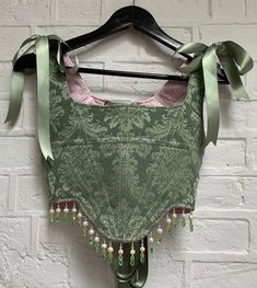 Made-to-order boned corset in sage green brocade. Embellished by hand around the hem with a combination of pink, green and freshwater pearl beading. Lace up back and tie straps fastened with satin ribbon. I would recommend sending me your measurements (last photo) so your piece can be bespoke to your size. I can also work from your trouser size, clothing size, bra size and height if necessary.  Please allow up to 4 weeks for your piece to be made and shipped. Every piece is made-to-order with lo Brocade Corset, Diy Corset, Ren Faire Outfits, Fair Outfits, Pearl Beading, Corset Outfit, Fairytale Fashion, Sewing Design, Corset Lingerie