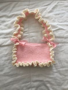 a crocheted purse with a pink bow on the front and white trim around it