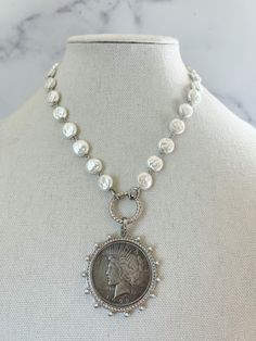 Vintage Coin Necklace detailed in beautiful CZ and porcelain glass pearls. This coin is a reproduction piece, and holds the weight of a true coin! The reproduction coin pendant is detailed with CZ stones and tiny glass pearls. It is connected with a silver spring lock clasp. Vintage porcelain glass pearls on a rosary style chain with silver hat details. We offer various lengths in this necklace so you can style it how you want :) Details: + Vintage Porcelain Glass Pearl Chain with silver detail Silver Medallion Jewelry With Pearl Chain, Silver Medallion Necklace With Pearl Charm, Antique Silver Pearl Jewelry, White Round Coin Pendant Necklace, White Round Coin Necklace, Vintage Charm Necklace, Large Necklaces, Mama Jewelry, Medallion Jewelry