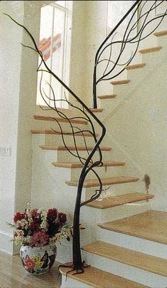 there is a vase with flowers on the floor next to a stair case and railing