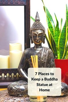 buddha statue sitting on top of a table next to a potted plant and candle