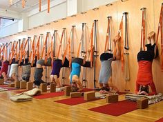 a group of people doing yoga poses in front of a wall with orange ribbons on it