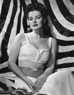 a black and white photo of a woman sitting on a zebra print background with her hands in her pockets