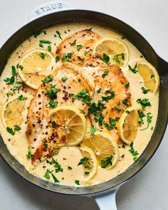 a skillet filled with chicken and lemons on top of a white countertop