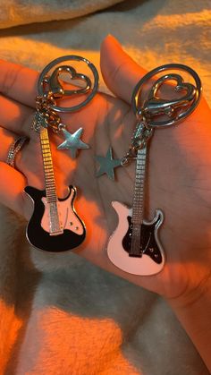 two key chains with guitars on them are being held in the palm of someone's hand