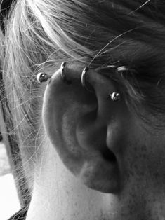 a close up of a person's ear with two piercings on it and one behind the ear