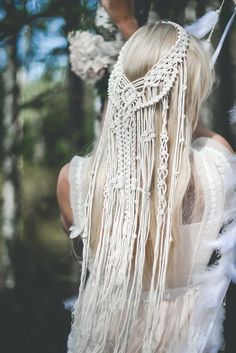 a woman with long blonde hair wearing a white dress and feathered headdress