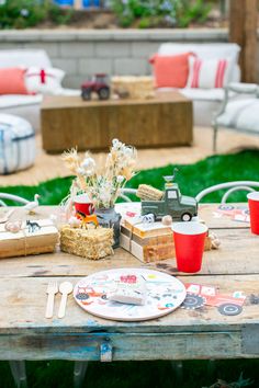 a picnic table with plates, cups and utensils on it in the backyard