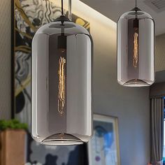 two clear glass pendant lights hanging from a ceiling in a living room or dining room