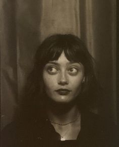 black and white photograph of a woman with long hair looking at the camera while wearing necklaces