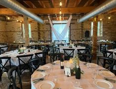 tables and chairs are set up for an event with white tablecloths, silverware and wine bottles