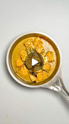 a pan filled with food sitting on top of a white counter next to a spoon