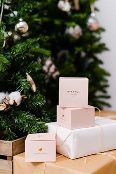 three wrapped presents sitting on top of a wooden box next to a christmas tree with ornaments