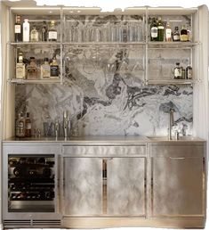 a kitchen with marble counter tops and shelves filled with wine glasses, bottles and liquor