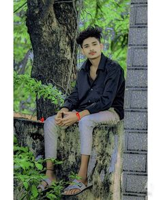 a young man sitting on top of a tree