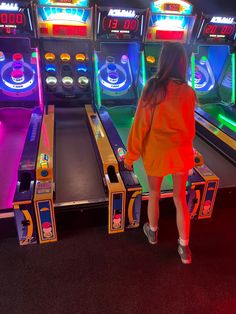 a woman is standing in front of some pinball machines with neon lights on them