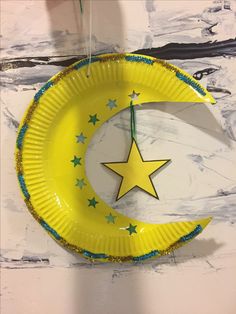 a paper plate with a yellow moon and stars hanging from it's side on a wall