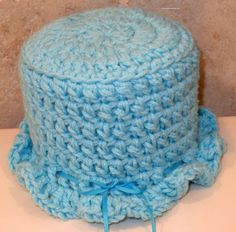 a crocheted blue hat with a bow on the brim is sitting on a table