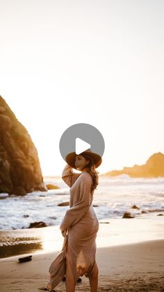 a woman in a dress and hat walking on the beach