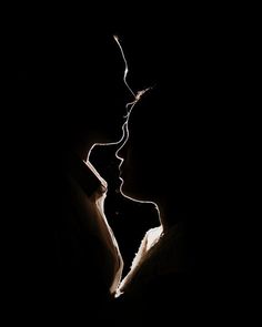 two people are kissing in the dark with their heads turned to each other and one person is