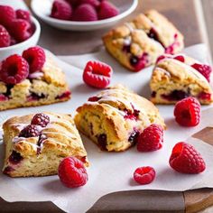 raspberry scones on parchment paper with bowls of berries