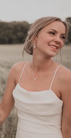 a woman in a white dress is smiling and holding her hand out to the side