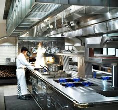 a chef is preparing food in a large stainless steel kitchen with stoves and ovens