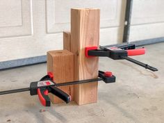 a couple of tools that are on top of a piece of wood in front of a garage door