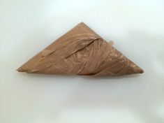 a piece of brown paper folded in a triangle shape on top of a white surface