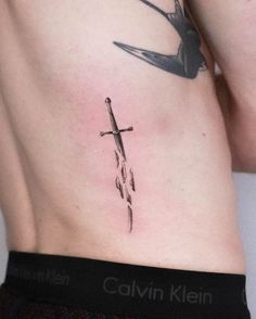 a cross tattoo on the side of a man's lower back ribcage