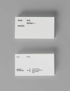 two white business cards sitting next to each other on top of a gray surface with the words, less but better - >