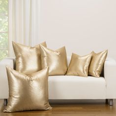 gold pillows on a white couch in front of a window