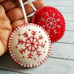 two red and white ornaments in the shape of snowflakes are being held by someone's hand