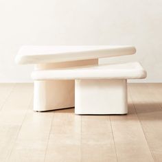 two white benches sitting on top of a hard wood floor