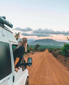 a woman looking out the window of a van on a dirt road