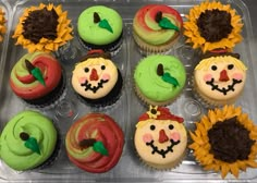 cupcakes decorated with sunflowers and frosting are in a plastic tray