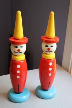 two wooden toy clowns sitting on top of a table