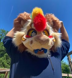 a person wearing a lion mask with a red hat on top of his head and blue shirt