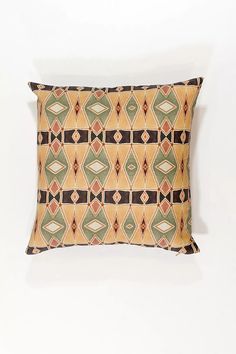 an orange and green decorative pillow on a white wall with a black border around it