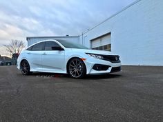 a white honda civic parked in front of a building