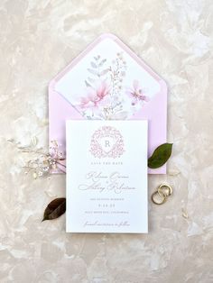 the wedding stationery is laid out on top of the table with flowers and leaves