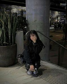 a woman sitting on the ground covering her face