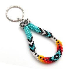 a beaded keychain is hanging from a metal ring on a white surface