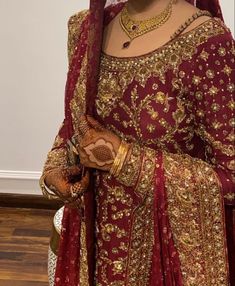 a woman wearing a red and gold bridal outfit